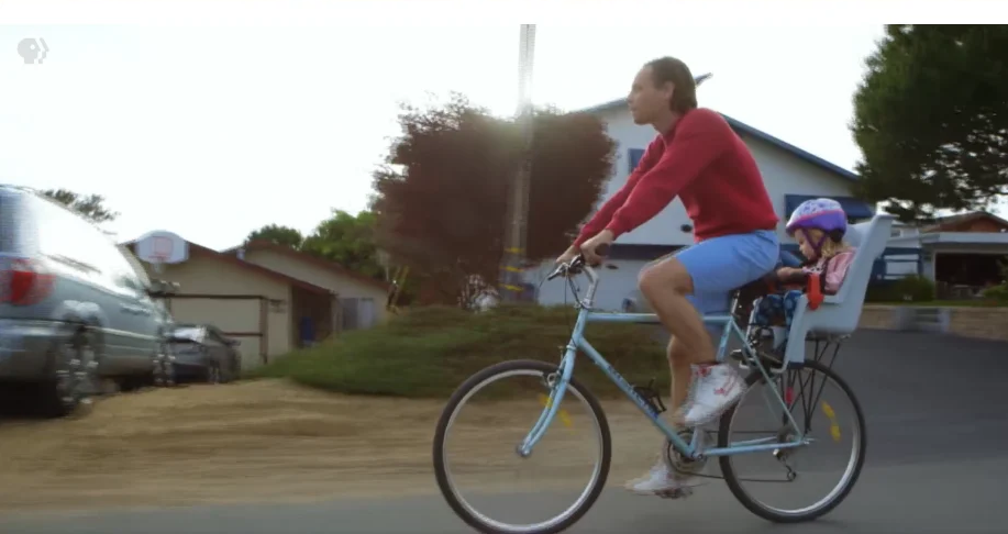 Matt riding a bike with his daughter